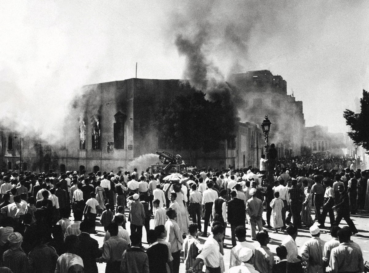 Crowds gather around the burning headquarters of the Muslim Brotherhood in Cairo, 27 October 1954.  It was set on fire after the attempted assassination of Gamal Abdel Nasser. Associated Press/Alamy.